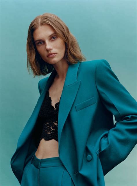 A Woman With Short Hair Wearing A Blue Suit And Black Lace Bra