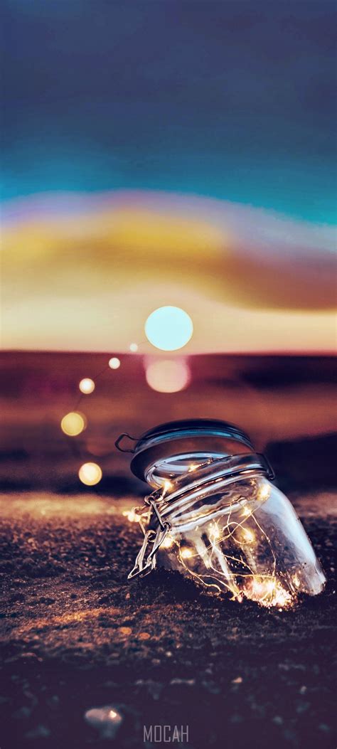 Mason Jar Half Buried In The Beach Sand With Pixie Lights After Sunset