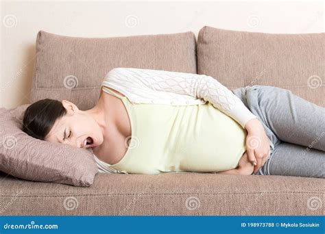 Beautiful Pregnant Woman Suffering Belly Ache Lying On A Sofa At Home