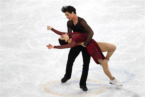 Two People Are Performing On The Ice In A Skating Rink With Their Arms Around Each Other