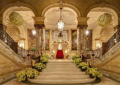 An Ornate Staircase Leading Up To A Red Carpeted Hall With Chandeliers