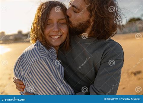 Close Up Of Couple In Love Hugging And Kissing While Walking Along The Beach On Sunny Windy Day