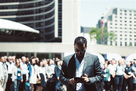 Selective Focus Photography Of Man Holding Smartphone While Standing
