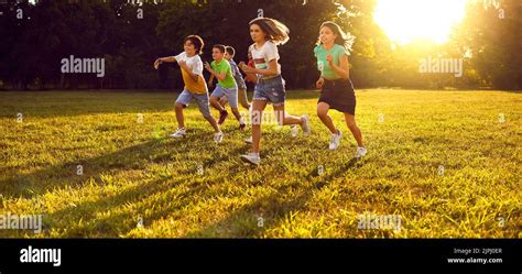 Group Of Happy Little Children Enjoying Summer Running In The Park And