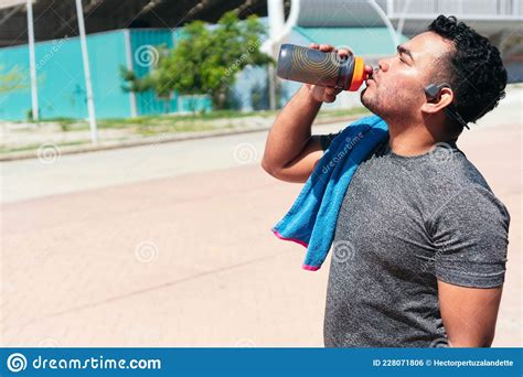 Fitness Man Drinking Water While Standing In The Park Cheerful