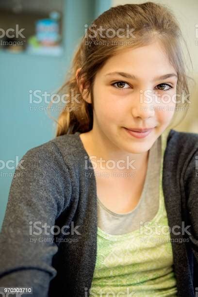 Portrait Of Preteen Girl In Classroom Sitting At Her Desk Stock Photo