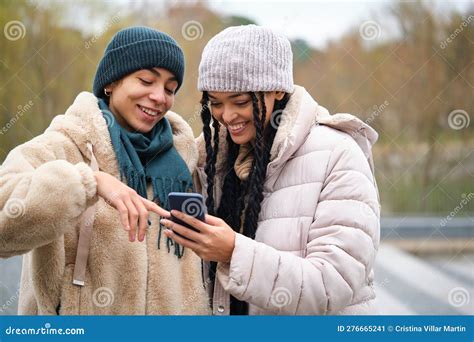 happy dominican lesbian couple using the phone at street in winter stock image image of laugh