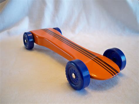 An Orange Skateboard Sitting On Top Of A White Sheet With Blue Wheels