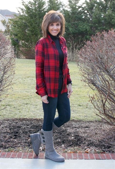 A Woman Standing In Front Of A Bush Wearing Boots And A Red Plaid Shirt