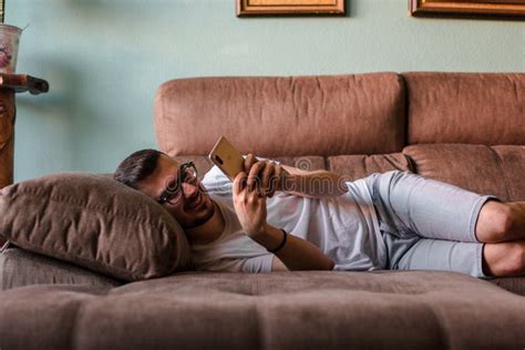 Man Using Mobile Phone While Lying On Sofa At Home Stock Image Image