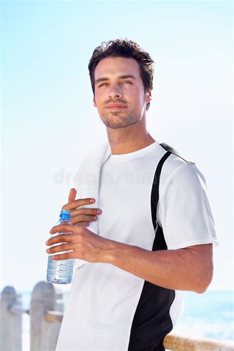 Keeping Hydrated A Young Man Drinking A Glass Of Water Stock Photo