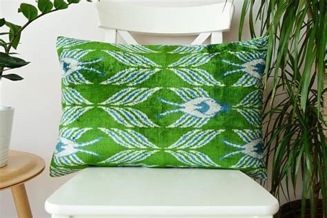 A Green And Blue Pillow Sitting On Top Of A White Chair Next To A