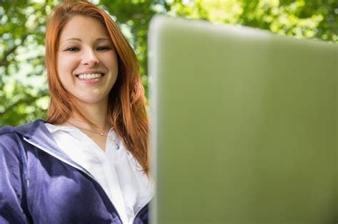 Premium Photo Pretty Redhead Relaxing In The Park Using Laptop