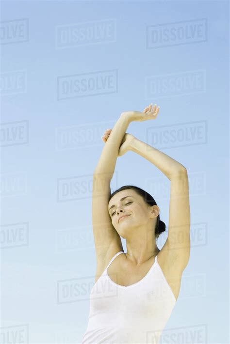 Woman Stretching Arms Overhead Sky In Background Low Angle View Stock Photo Dissolve