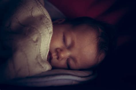 Newborn Baby Peaceful Sleeping In Dark Room With Low Natural Light