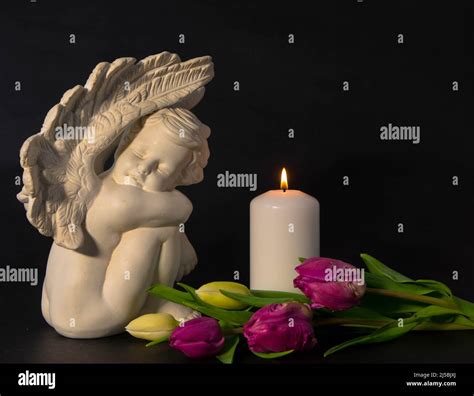Angel with burning candle against black background. Moment of sorrow at