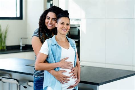 Premium Photo Portrait Of Pregnant Lesbian Couple Embracing In Kitchen