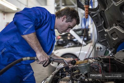 Car Mechanic In A Workshop Repairing Car — Working Clothes People