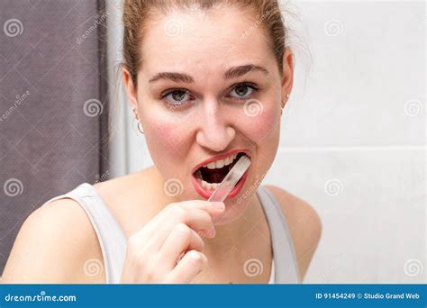 Focused Beautiful Young Woman Brushing Her Teeth With Care Stock Image