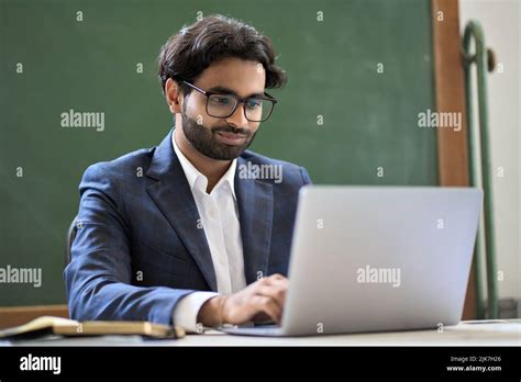 Young Indian Business Man In Suit Working On Laptop Computer Sitting In