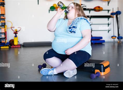 Full Length Portrait Of Exhausted Obese Woman Sitting On Step And Drinking Water After Extreme