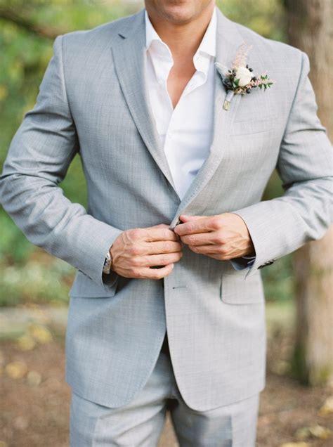 A Man In A Gray Suit And Flower Boutonniere Is Posing For The Camera