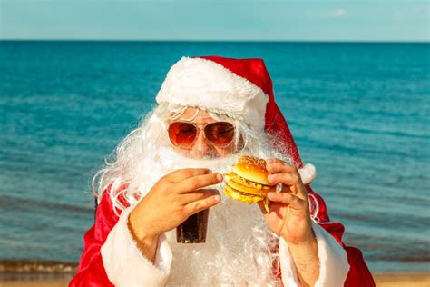 Santa Claus Na Praia Que Come Um Hamburger Imagem De Stock Imagem De