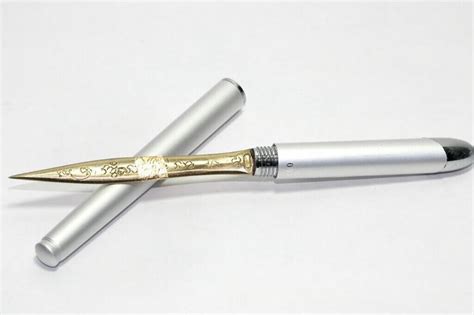 Two Silver And Gold Pens Sitting Next To Each Other On Top Of A White