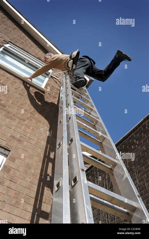 WORKMAN OVER BALANCING ON LADDERS WORKING ON HOUSE RE LADDER SAFETY Stock Photo Royalty Free