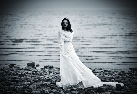 Beautiful Sad Girl In White Dress Standing On Sea Coast Stock Photo