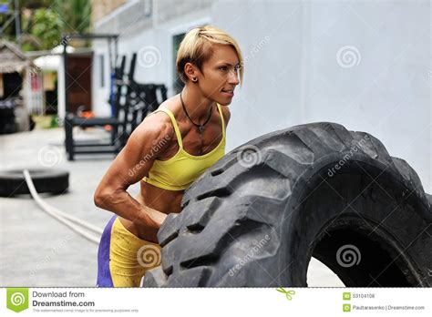 Athlete Female Working Out With A Huge Tire Turning And Flippin Stock