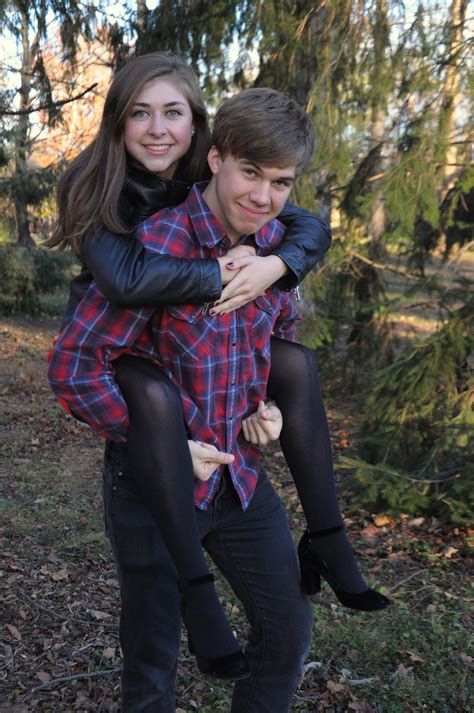 A Man And Woman Are Sitting On Top Of Each Other In The Woods With