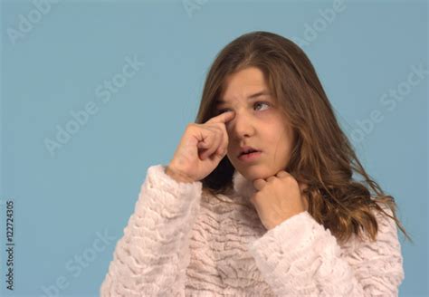 Girl Rubbing Her Itchy Eye Against A Blue Background The Girl Was Ten