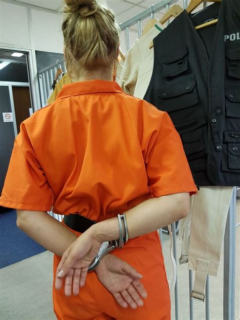 Woman In Prisoner Dress Has Her Hands Cuffed Behind Back With An Obsolete Gdr Hinged Handcuff