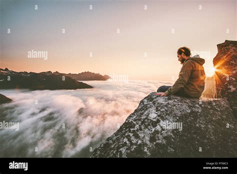 Man Thinking Sitting Alone On Cliff Edge Mountain Top Above Clouds
