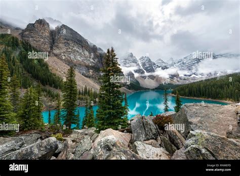 Clouds Hanging Between The Mountain Peaks Reflection In Turquoise