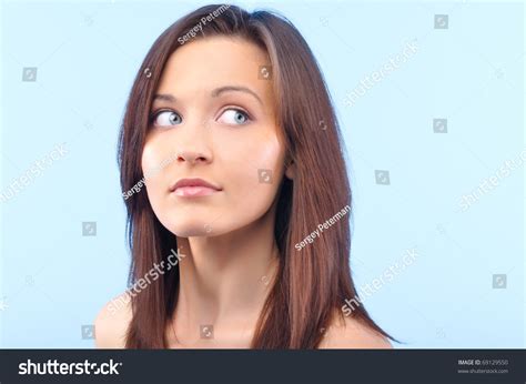 Beautiful Happy Woman Is Looking Sideways And Touching Her Face On Blue