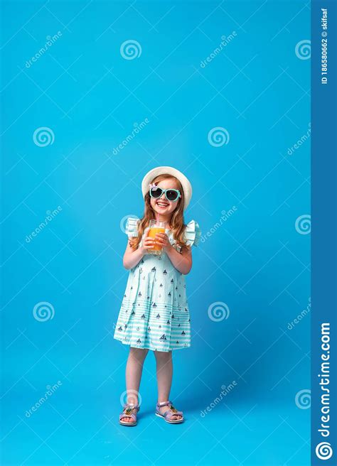 Cute Little Girl In A Dress Hat And Sunglasses Poses On A Pink