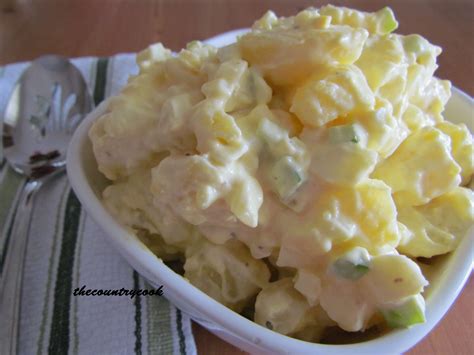 A White Bowl Filled With Potato Salad On Top Of A Table