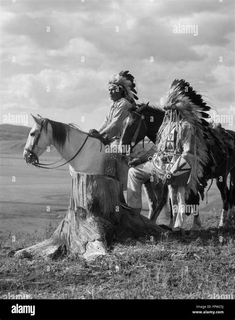 1920s two native american stoney sioux indian men in full feather war bonnets standing with