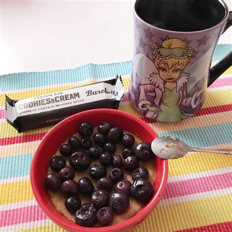 A Bowl Of Blueberries Next To A Cup Of Coffee And A Bar Wrapper