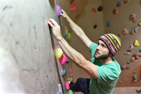 Bouldern In Einer Kletterhalle Junger Mann Klettert Eine Knstliche