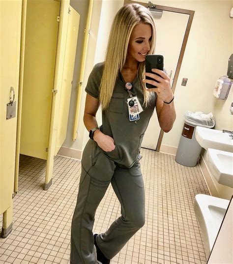 A Woman Taking A Selfie In The Bathroom While Wearing Scrubs And