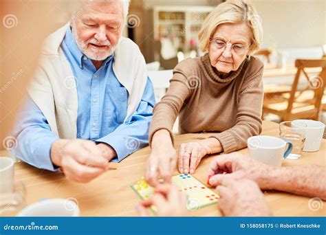 Seniors Play Board Game In Retirement Home Or Retirement Home Stock