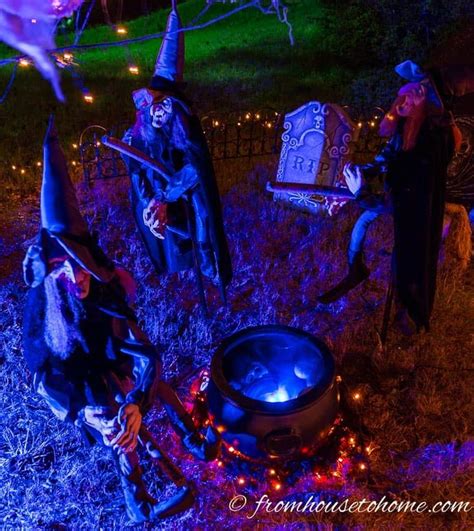 some people dressed up as witches in the yard at halloween time with lights and decorations