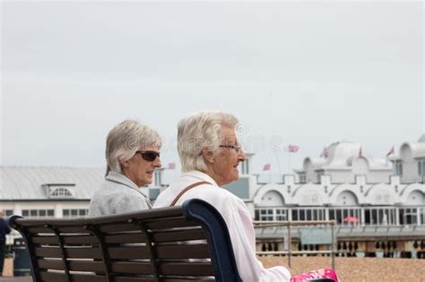 Two Elderly Ladies Or Women Sat On A Bench Talking At The English