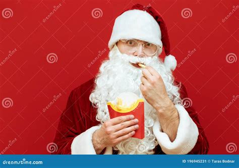 Funny Santa Claus Eating Fast Food On A Red Background Bites French
