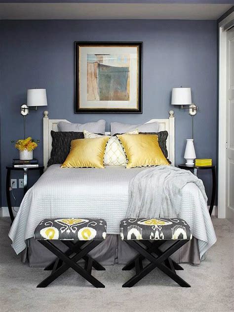 A Bedroom With Blue Walls And Yellow Pillows On The Bed Two Stools In