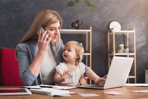 Счастливая мать работающая в офисе с ребенком молодая женщина разговаривает по телефону и с
