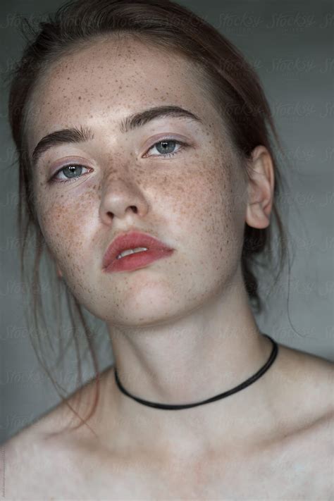 A Woman With Freckles On Her Face Wearing A Black Choker And Necklace
